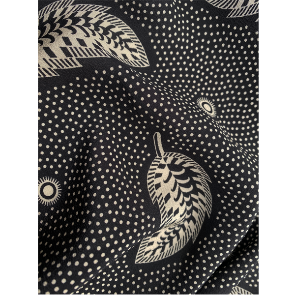 A Close-up graphic Cressida Bell silk shawl made in the UK from luxurious 100% silk crepe de chine printed with a hand-painted Stripey Leaf design in Black, bringing a touch of maximalism to any look  showing how the fabric falls