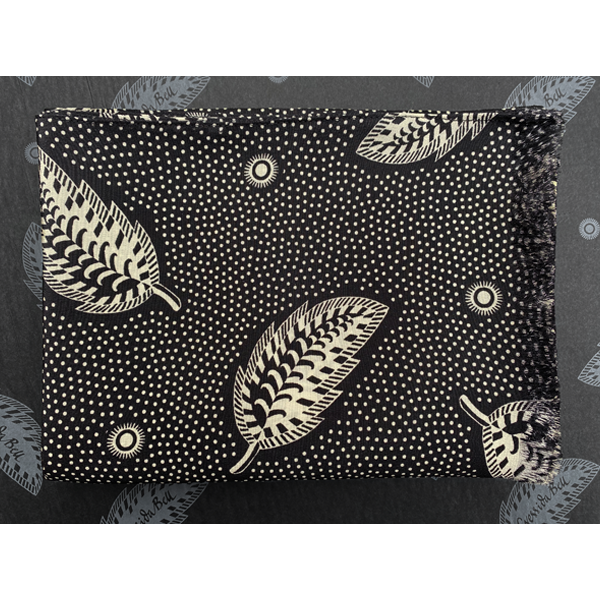 A graphic Cressida Bell silk shawl made in the UK from luxurious 100% silk crepe de chine printed with a hand-painted Stripey Leaf design in Black bringing a touch of maximalism to any look  photographed folded on top of wrapping paper
